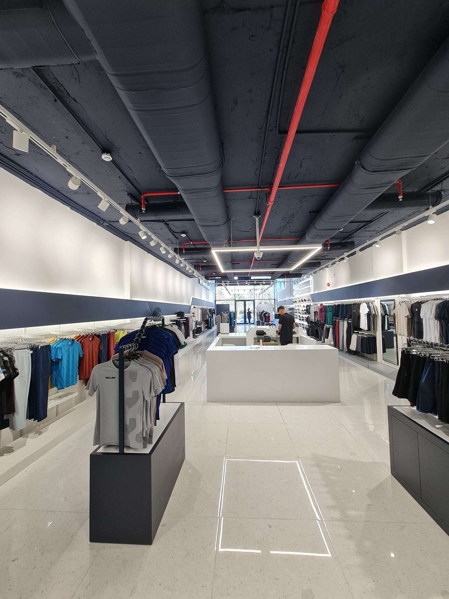 An ARAK-lit retail showroom in Riyadh with track spots, linear runs and shelf-integrated strips, seen from the shop floor